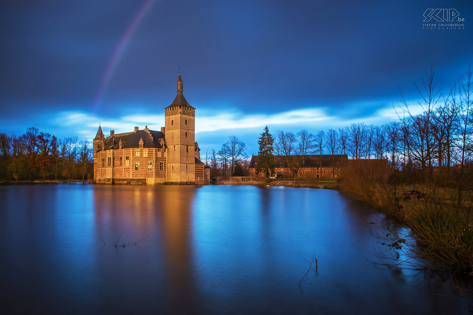 Sint-Pieters-Rode - Castle of Horst with rainbow just before sunset The castle and the chapel of Horst are photogenic landmarks near my new home. So in recent months I went out to photograph them several times, mostly in the evening and at night or when there were special weather conditions. I tried to create some unique photos of these monuments that differ from the images that already have been captured by many other people.<br />
 <br />
The castle of Horst is located in the village of Sint-Pieters-Rode (Holsbeek, Belgium). The castle was built in the mid-14th century and is still quite authentic. The former living rooms, made of brick and sandstone, are mostly from the 16th and 17th centuries. After a heavy rainshower a rainbow appeared above the castle and the last light of the sun gave the castle a beautiful orange-yellow glow. Stefan Cruysberghs